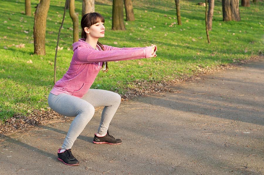 Mulher adulta em posição de agachamento no parque